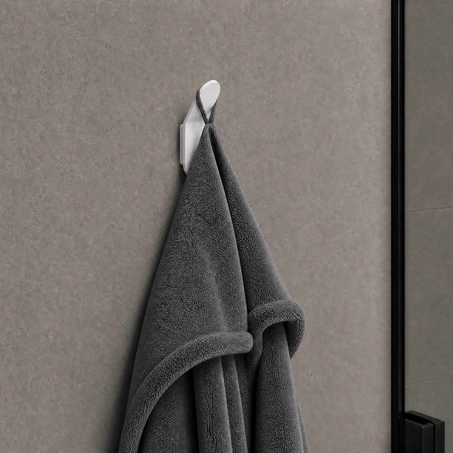 Gray towel hanging on a white hook against a gray wall.