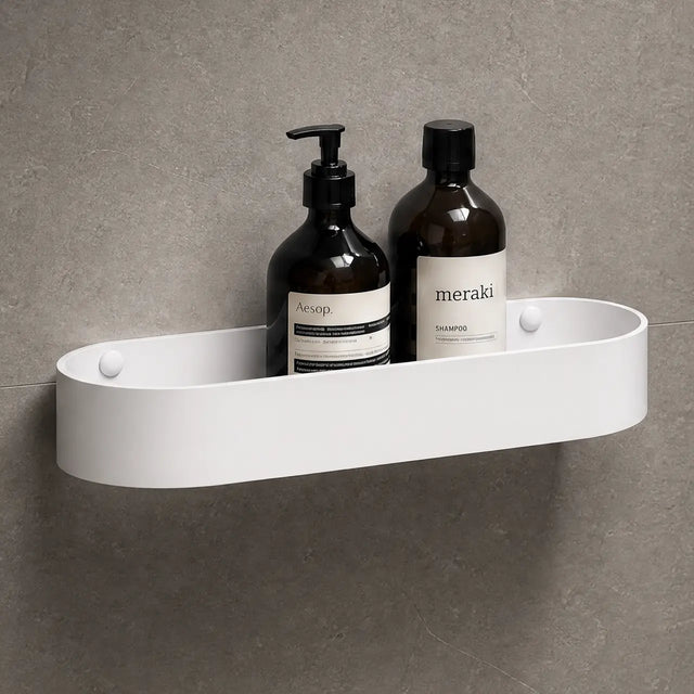 White shower caddy with bottles on a gray wall with a black shower head.