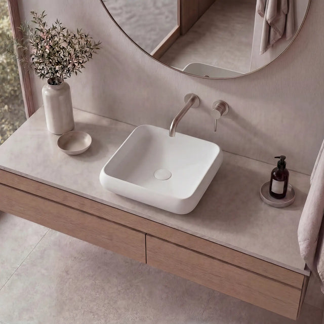 Bathroom vanity with a square sink, faucet, and decorative items.