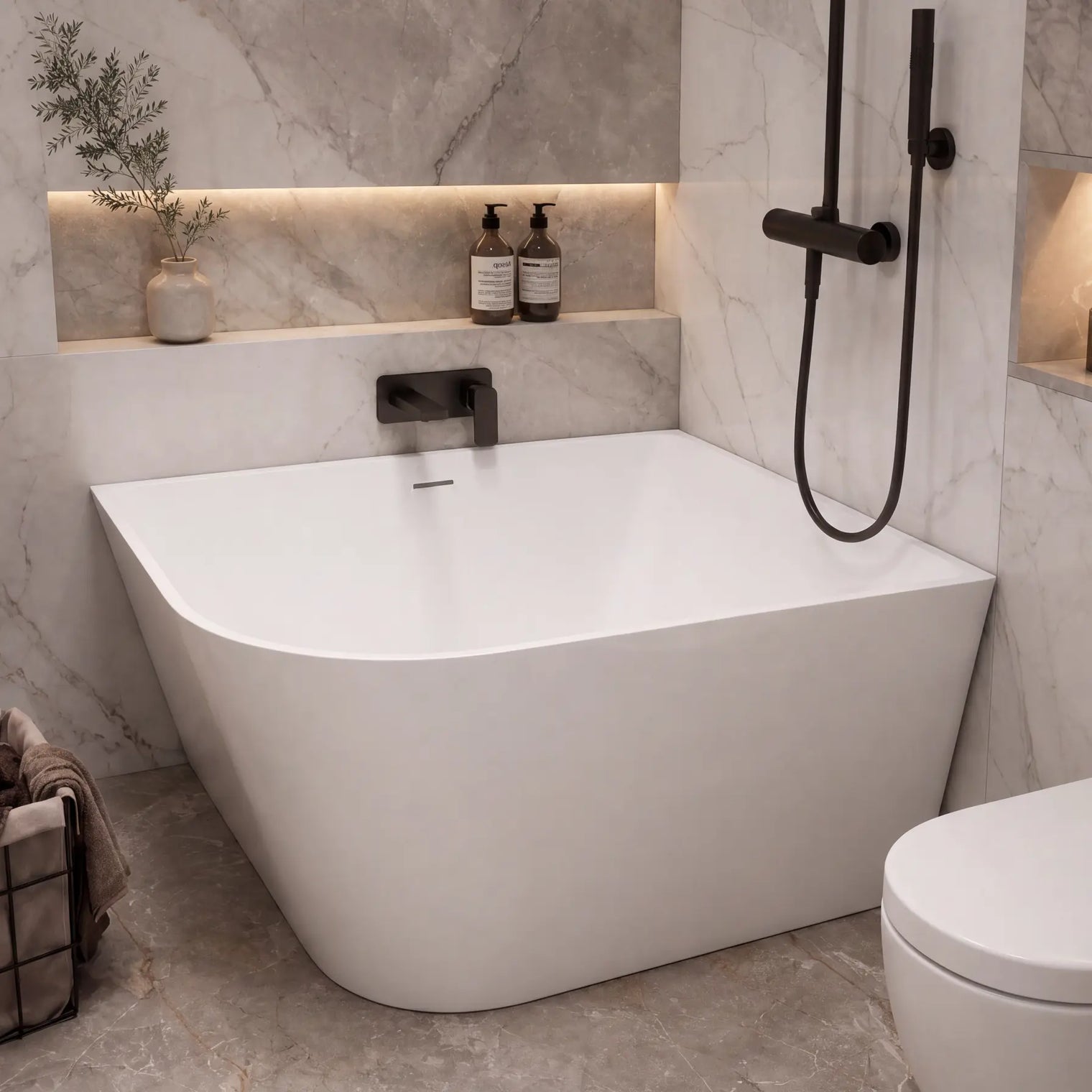 A modern freestanding bathtub in a marble-look bathroom with a black handheld shower, toilet, built-in shelves, and small decorative bottles.