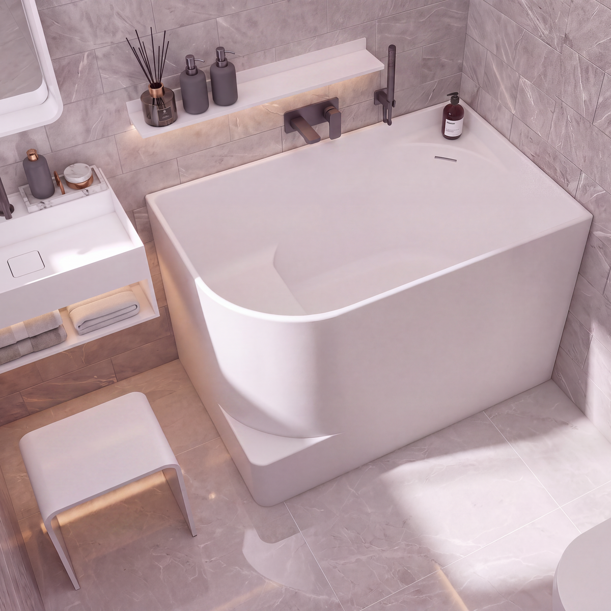 A modern freestanding bathtub in a minimalist bathroom setting with gray marble-look tiled walls and floor, a white vanity, and a small white stool.