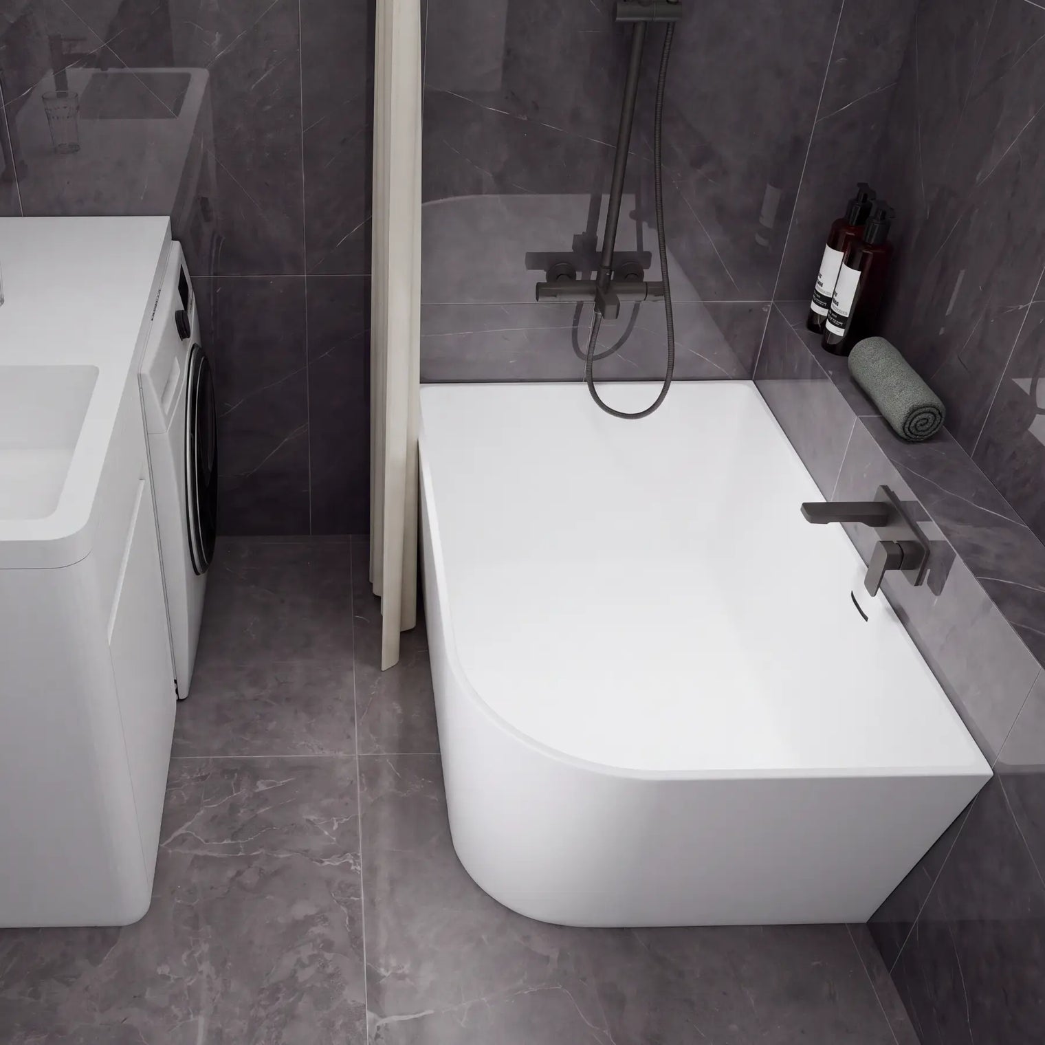 A modern bathroom setup featuring a white freestanding bathtub with a dark wall-mounted faucet and shower system, alongside a white sink vanity with a matching dark faucet and a small washing machine, all set against dark gray tiled walls and floor.