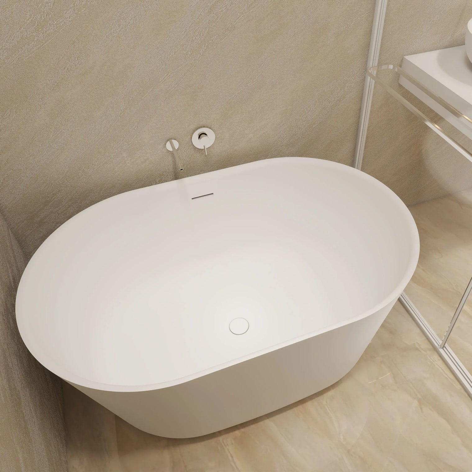 A modern freestanding oval bathtub in white, shown installed in a minimalist bathroom with beige textured walls and light wood flooring.