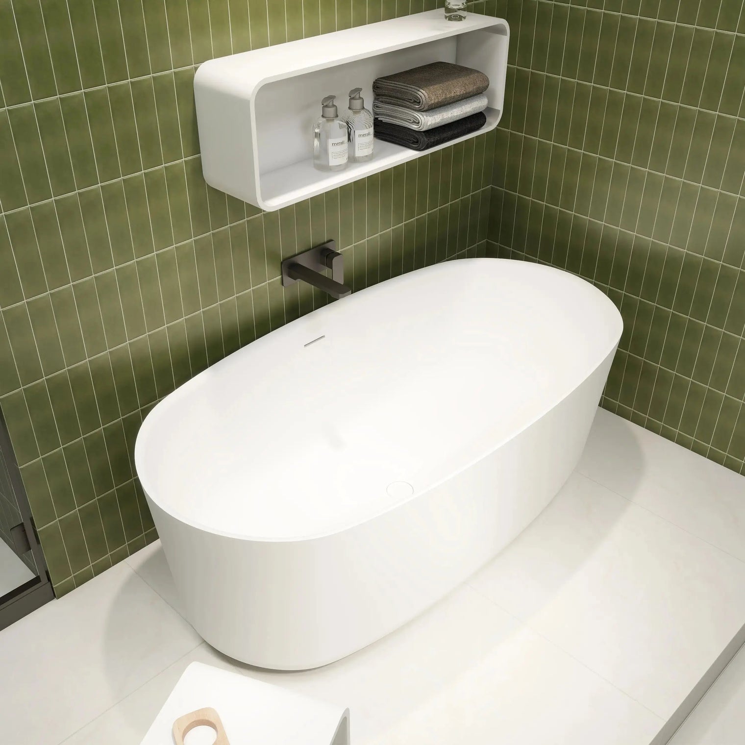 Modern white freestanding bathtub in a bathroom with green tiled walls.