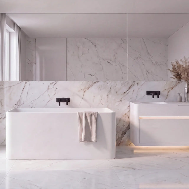 A modern bathroom interior with a white freestanding bathtub, a matching white vanity cabinet with integrated sink, marble-look wall and floor, black faucet fixtures, sheer curtains, and a mirror.