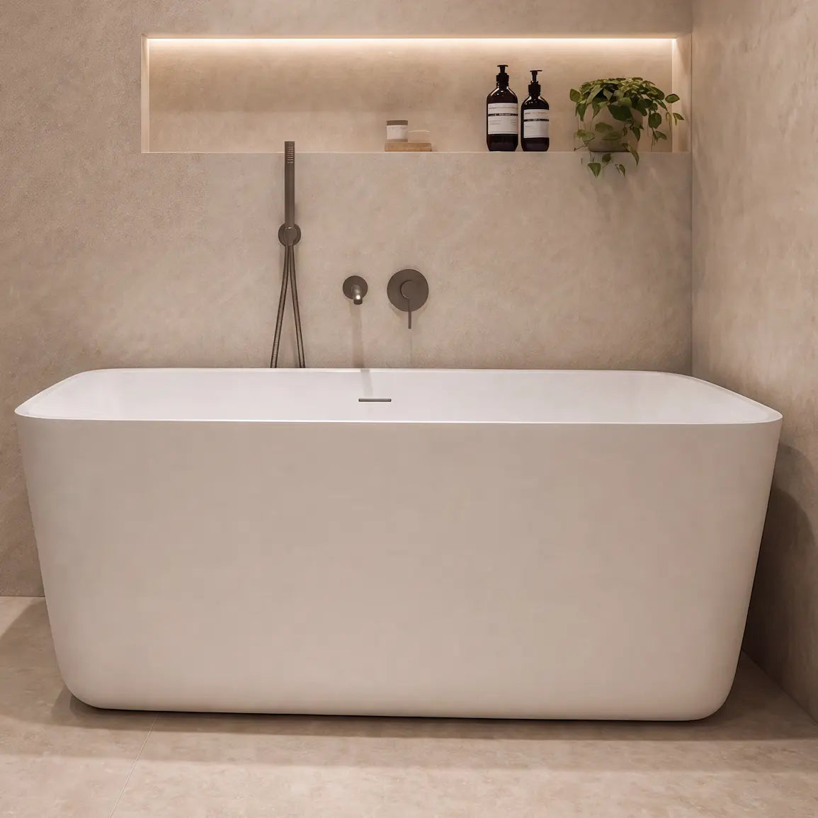 A modern freestanding bathtub in a minimalist beige-toned bathroom with a glass shower enclosure, built-in shelving, and warm ambient lighting.