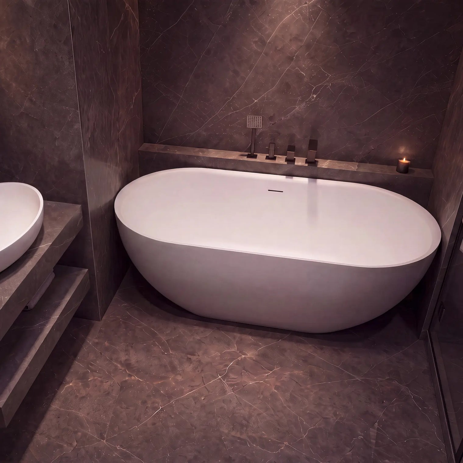 A modern freestanding oval bathtub in a dark stone bathroom with a matching stone vessel sink and floating vanity.