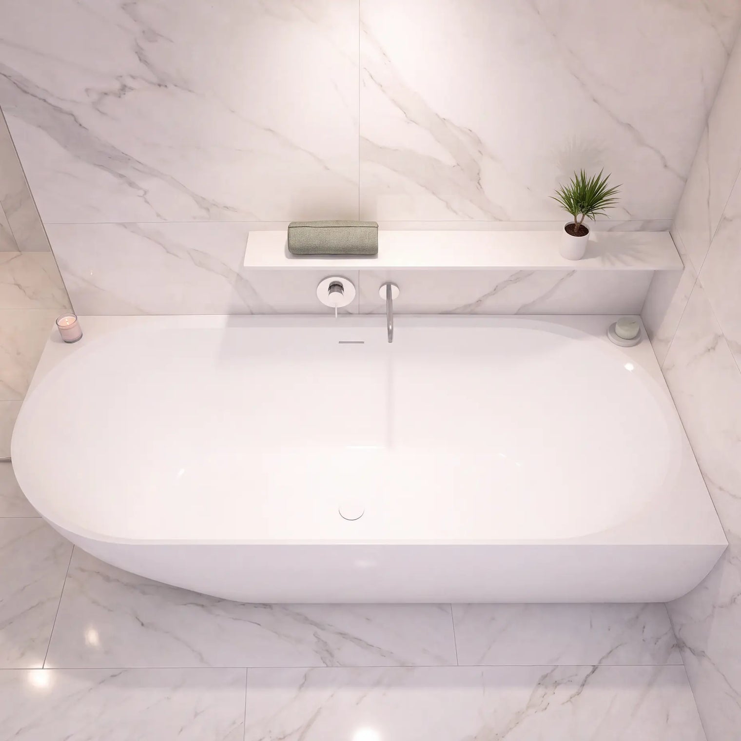 A modern freestanding white bathtub set in a bright bathroom with white marble walls and floor, featuring a built-in shelf with a small plant and soap dispenser.