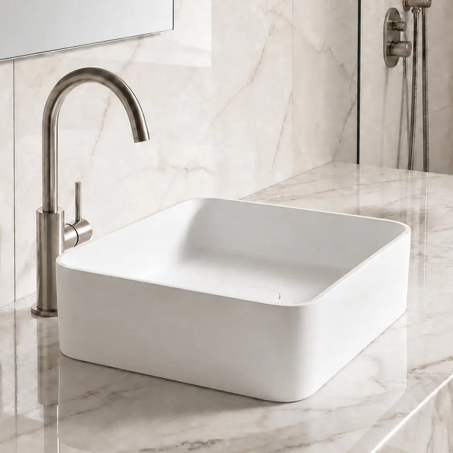 White Solid Surfaces rectangular sink on a marble countertop with a silver faucet.