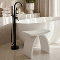 Modern bathroom with a freestanding bathtub, black faucet, and decorative plants.