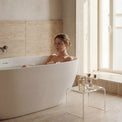 Woman relaxing in a freestanding bathtub in a modern bathroom.