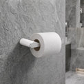 Roll of toilet paper on a holder against a tiled bathroom wall.
