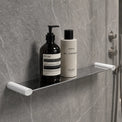 Bathroom shelf with Aesop products against a gray tiled wall.