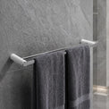 Gray towels hanging on a towel rack in a bathroom with tiled walls and floor.