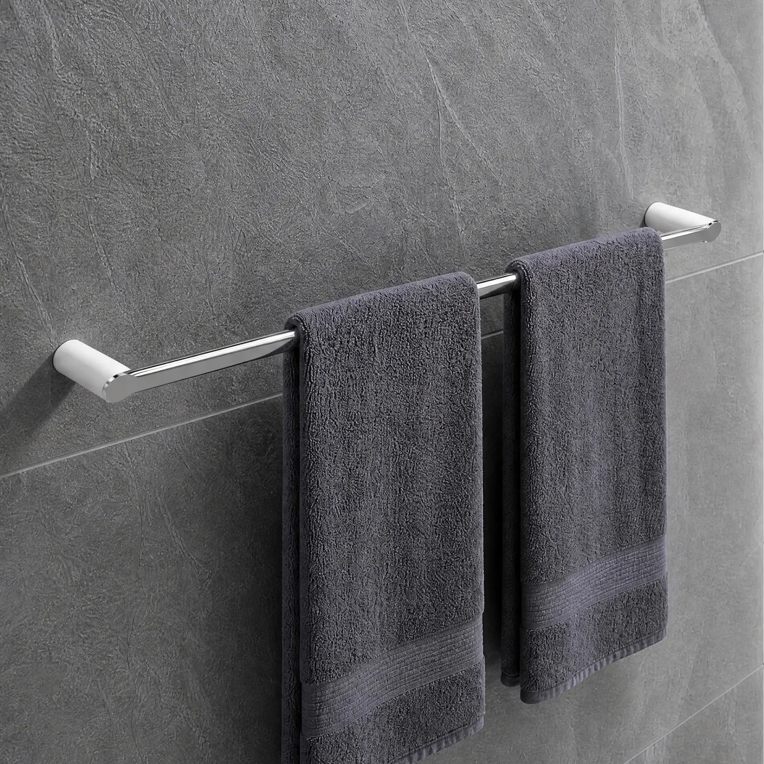 Gray towels hanging on a towel rack in a modern bathroom with tiled walls and a shower.