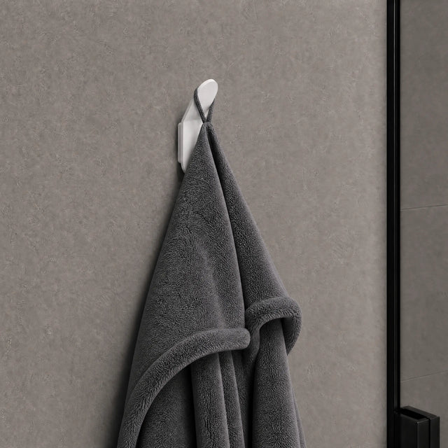 Gray towel hanging on a white hook against a gray wall.