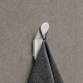 Gray towel hanging on a white hook against a gray wall.