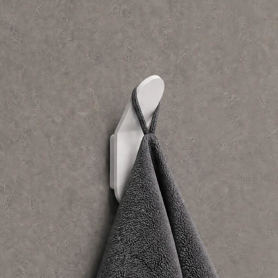 Gray towel hanging on a white hook against a gray wall.