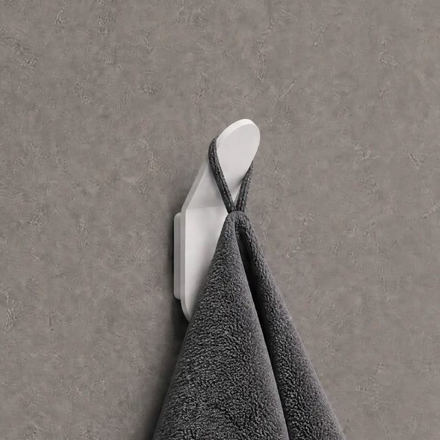 Gray towel hanging on a white hook against a gray wall.
