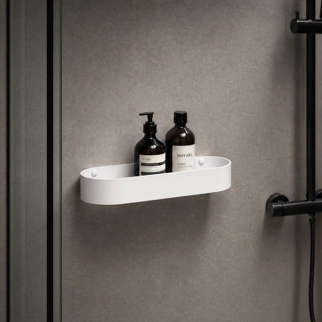White shower caddy with bottles on a gray wall with a black shower head.