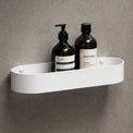 White shower caddy with bottles on a gray wall with a black shower head.
