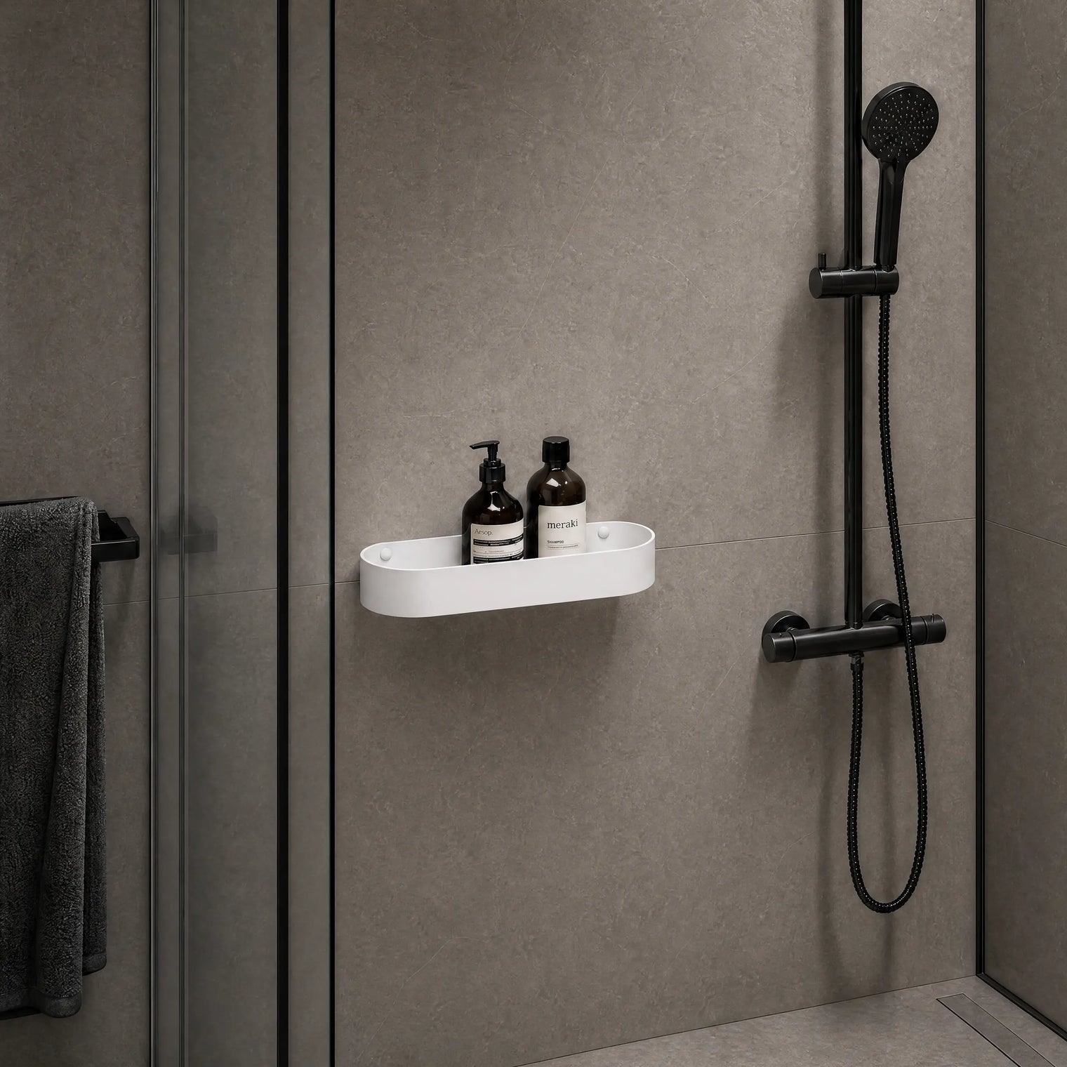 Shower setup with a white shelf holding bottles against a gray wall.