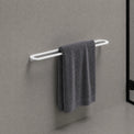 Gray towel hanging on a white towel rack against a gray wall.