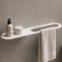 Bathroom setup with a shelf, towel, and toiletries against a gray wall.
