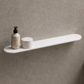 White shelf on a gray wall with bathroom items and a mirror.
