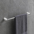 Gray towel hanging on a towel rack in a modern bathroom with tiled walls.