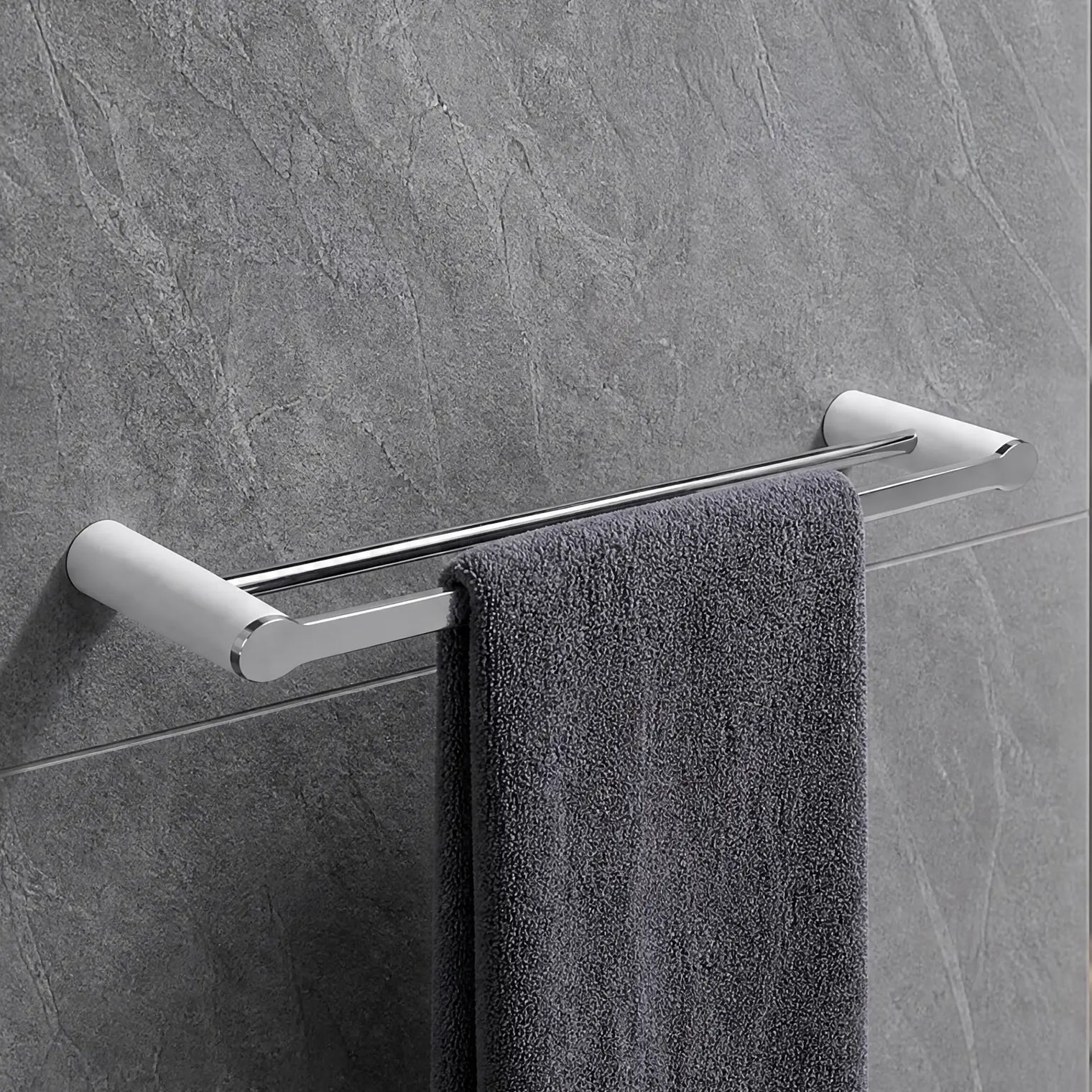 Gray towel hanging on a towel rack in a modern bathroom with gray tiles.