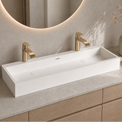 Bathroom vanity with white rectangular sink, gold faucets, and decorative elements.