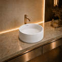 Modern bathroom vanity with a white solid surfaces sink and gold faucet.