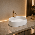 Modern bathroom solid surfaces sink with gold faucet on a marble countertop