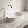 White Solid Surfaces oval sink on a marble countertop with a matching wall.