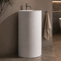 Modern bathroom with a freestanding bathtub, sink, and circular mirror.