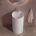 Modern bathroom with a round mirror, white freestanding sink, and decorative plant.