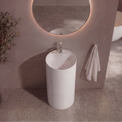 Modern bathroom with a round mirror, white freestanding sink, and decorative plant.