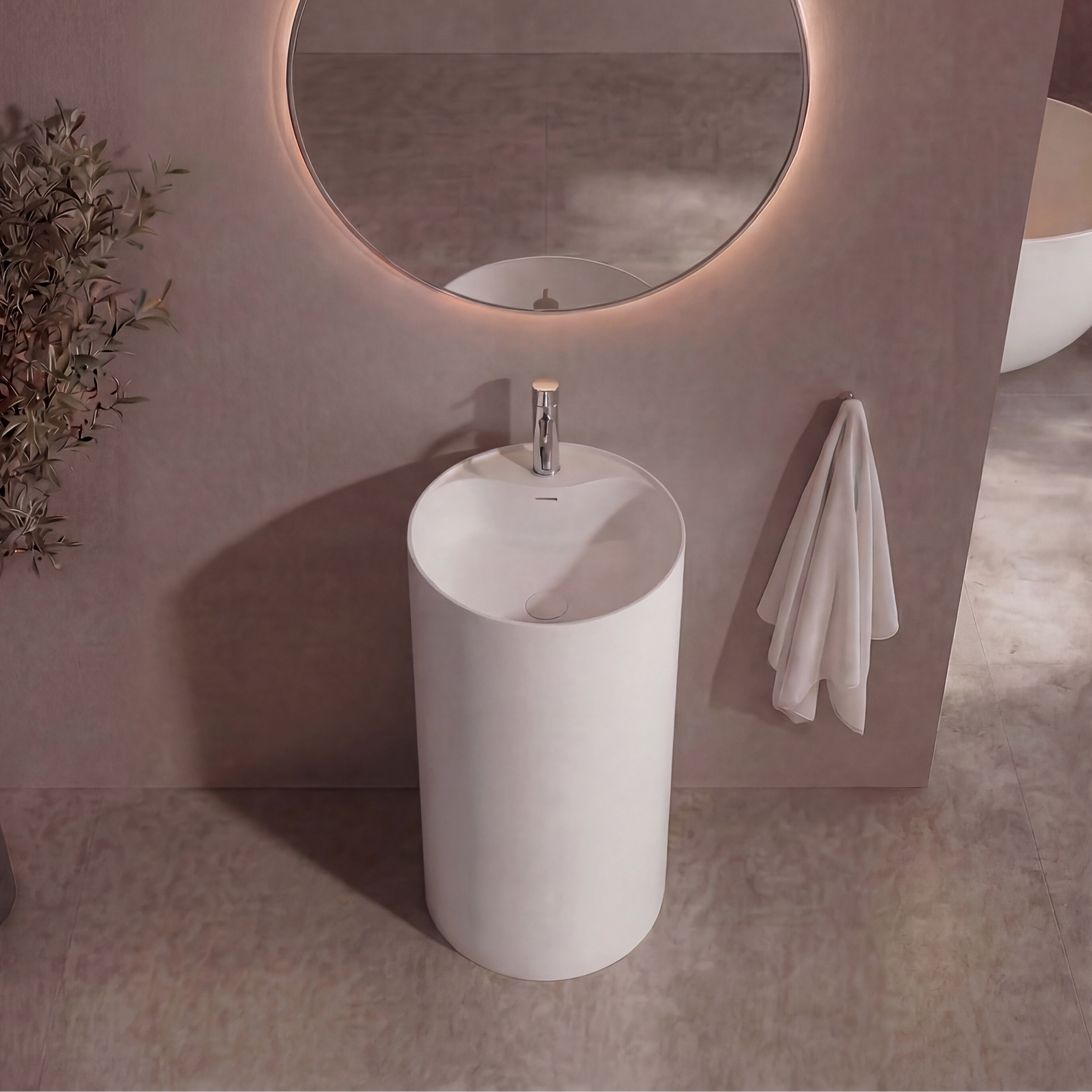 Modern bathroom with a round mirror, white freestanding sink, and decorative plant.