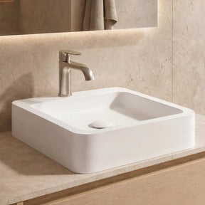 Bathroom vanity with a white sink, light wood cabinets, and decorative elements.
