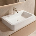 Bathroom vanity with a white sink and wooden cabinet, featuring a neutral color scheme.