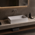 Bathroom vanity with a rectangular solid surfaces sink, faucet, and minimal decor.