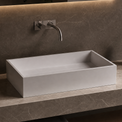 Bathroom vanity with a rectangular solid surfaces sink, faucet, and minimal decor.