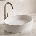 White Solid Surfaces oval sink on a marble countertop with a silver faucet.
