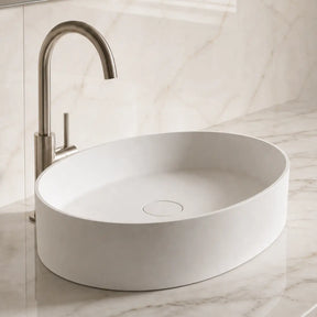 White Solid Surfaces oval sink on a marble countertop with a silver faucet.