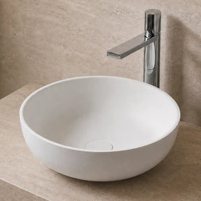 Bathroom with a white solid surfaces sink on a stone countertop, illuminated by warm lighting.