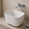 Modern bathroom with a white freestanding Solid Surfaces sink, faucet, and decorative elements.