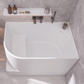 A modern bathroom scene with a large white freestanding bathtub, a white wall-mounted sink, gray stone tile walls and floor, and a few small bathroom accessories and towels.