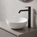 Modern bathroom with a floating vanity, round mirror, and plant.