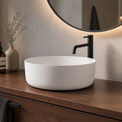 Bathroom vanity with a white sink, black faucet, and decorative items.